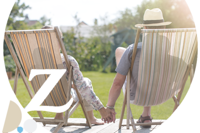 dos personas mayores tumbados en hamacas dándose la mano