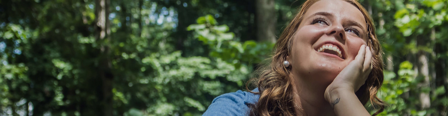 Mujer feliz y emocionada en el bosque