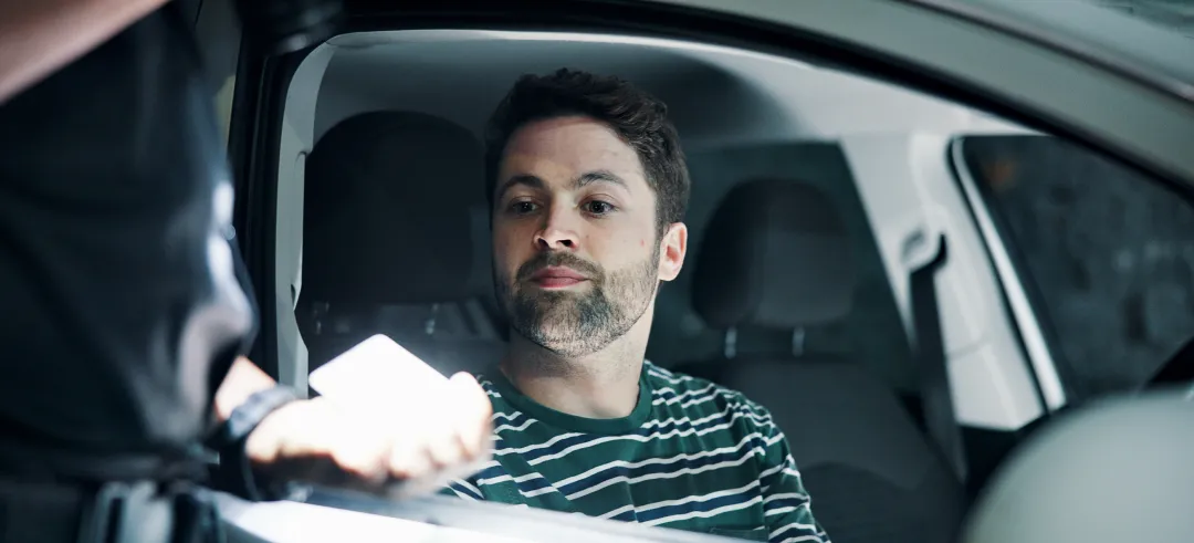 Conductor dentro del coche entregando la documentación a un agente de tráfico por una posible multa