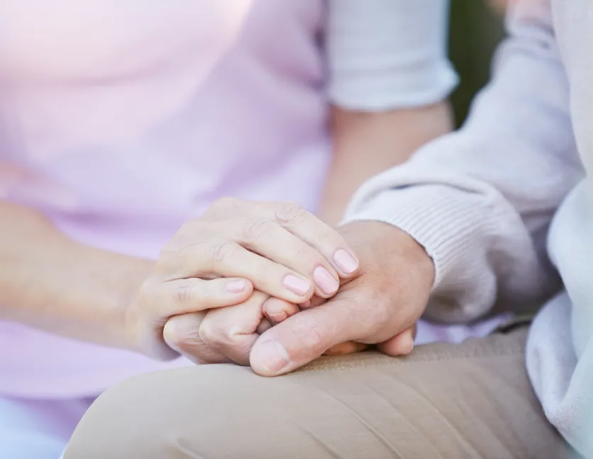 Mano de una persona sujetando con ternura la de un adulto mayor