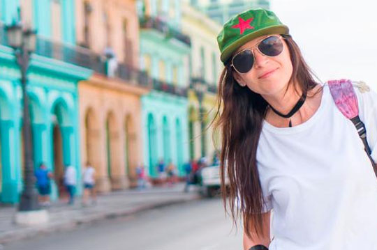 Chica joven sacándose una foto con gafas y gorra en Cuba